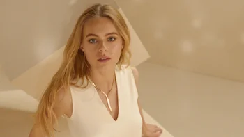 Chaumet Bee My Love commercial still of blonde girl standing in beige world and staring into camera