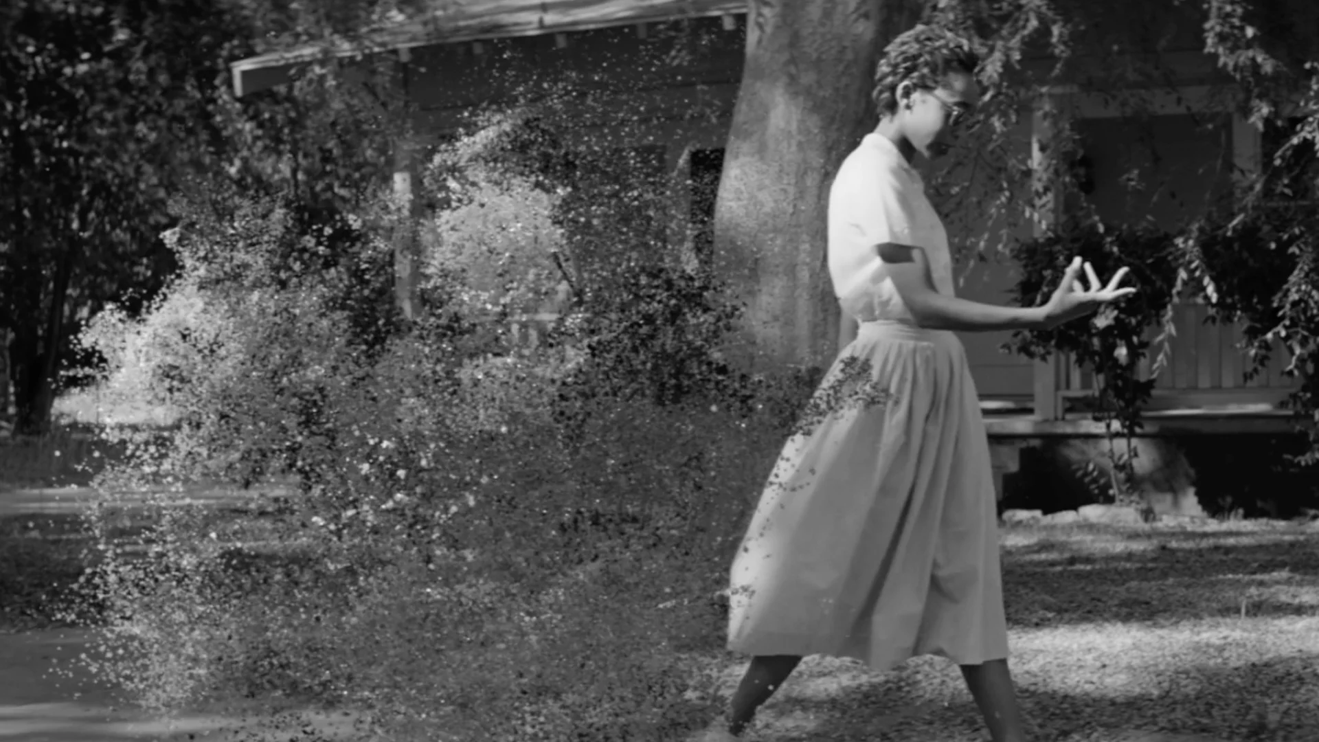 The First Day black and white still of Elizabeth Eckford walking past an explosion of pixels directed by Barnaby Roper