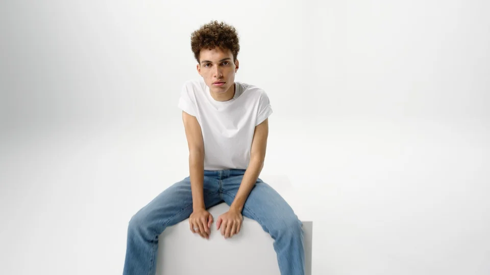 Vichy Normarderm campaign color still of young male model posing on a white cube and background by director Barnaby Roper